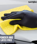 SAFESKIN black nitrile disposable glove wiping car hood with yellow microfiber cloth.