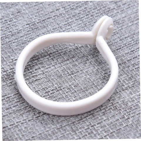 Single white ring from 60 Pack Plastic Circular Curtain Rings For Rods With Smooth Glide No Burr displayed on a textured surface