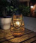 Outdoor Solar Rattan Lantern With Handle For Hanging Or Table Use, Cozy Chill Edison Bulb Glow, on a wooden patio table at night