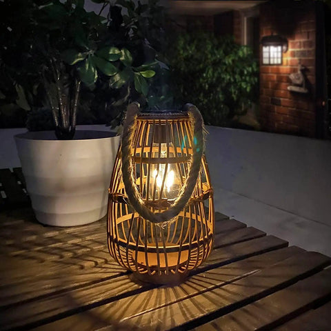 Outdoor Solar Rattan Lantern With Handle For Hanging Or Table Use, Cozy Chill Edison Bulb Glow, on a wooden patio table at night
