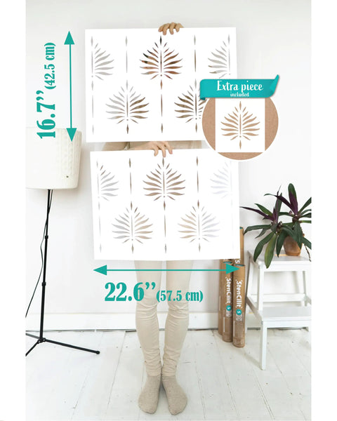 Person holding Fern Wall Stencil Set 2 Pack 17 By 22.5 Inches for painting large patterns indoors, featuring fern design.