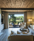 Living room with rustic walnut wood ceiling, modern sofa, and large windows showcasing nature views, highlighting interior design elegance.