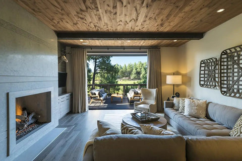 Living room with rustic walnut wood ceiling, modern sofa, and large windows showcasing nature views, highlighting interior design elegance.