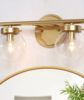 Two-Light Gold Vanity Light With Clear Globe Glass Shades Over-Mirror Fixture In Hand-Painted Gold Finish on wall