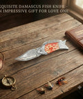 Copper Damascus Fish Style Folding Knife With Ladder Pattern Blade on rustic wooden table with fishing accessories