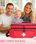Red large first aid bag with white cross, front view, dual zip pockets and shoulder strap, with family in background.