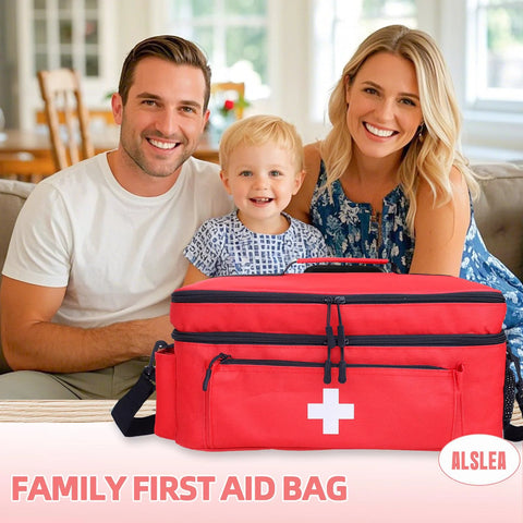 Red large first aid bag with white cross, front view, dual zip pockets and shoulder strap, with family in background.
