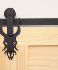 Close-up of a black rustic double track U shape bypass sliding barn door hardware kit installed on a wooden door with an imperial style roller.