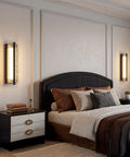 ElilyGiA 16 Inch Modern LED Wall Sconce Vanity Light, Black illuminating a stylish bedroom with decorative pillows and bedside decor.
