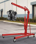 Heavy Duty Folding Hydraulic Engine Crane Hoist, 2 Ton Cherry Picker Rig lifting an engine, equipped with six pivoting caster wheels.