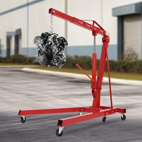 Heavy Duty Folding Hydraulic Engine Crane Hoist, 2 Ton Cherry Picker Rig lifting an engine, equipped with six pivoting caster wheels.