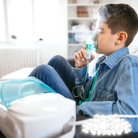 Boy using a nebulizer with bulk pack of 100 round white air filter sponges for compressor systems replacement filters visible