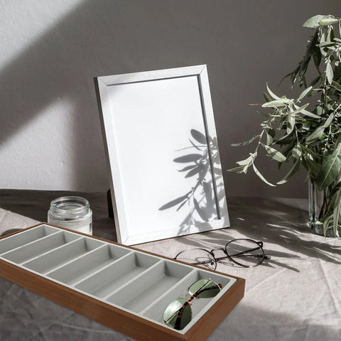 Keep Your Shades Neat In This Slick Wooden Sunglasses Holder Tray Featuring Plush Gray Velvet Lining And Seven Roomy Slots For Secure Eyewear Organization At Home on a table with a plant.