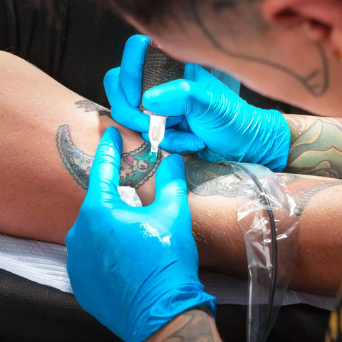 Tattoo artist wearing Large Nitrile Gloves Powder Free Latex Free 4 Mil 100 Count Exam Disposable Non Sterile For Medical Food Prep Cleaning And Home DIY Protection Everyday Home Use, tattooing an arm.