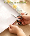 Self Adhesive Floral Peel And Stick Wallpaper Roll For Renters Featuring No Fuss Quick Install Water Resistant Scratch Proof Vinyl Wall Covering being cut with scissors.