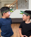 Two children wearing Roaring T Rex Dinosaur Headlamp For Kids And Adults LED Headlight Toy Flashlight With Super Bright Light.
