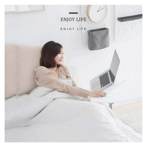 Slick Height Adjustable Laptop Table With Smooth Rolling Locking Casters Premium Couch Side Stand Heavy Duty Wood Finish Foldable Computer Cart For Lazy Day Lounging used in bed by a woman.