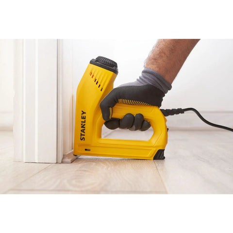 Heavy Duty Electric Staple And Brad Nail Gun With Dual Hi Lo Trigger For No Sweat Woodworking One Half Nine Sixteenths And Five Eighth Brads Eight Foot Cord Real Mule Power in use, stapling baseboard.