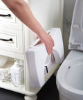 Person storing Foldable Toilet Stool Foot Rest Made For Real Squat Posture 7.5 Inch White Bathroom Hack next to toilet.