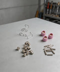 26-Pack Plasma Cutter Consumables Kit For AG60 SG55 CUT55 displaying copper electrodes, pink nozzles, and wire guides on a workspace.
