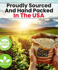 Hands holding a burlap sack of seeds with USA flag patch, farm field in background, labels 'Non-GMO Product' and 'Heirloom' visible.