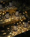 Six Pack Solar Powered Outdoor Pathway Lights Waterproof Black Lanterns casting star moon patterns on steps, night view.