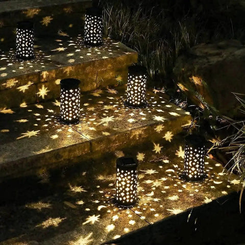 Six Pack Solar Powered Outdoor Pathway Lights Waterproof Black Lanterns casting star moon patterns on steps, night view.
