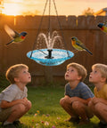 Children watch birds at a hanging bird bath fountain with glass bowl, USB powered cascading water feature for garden, patio, and yard décor.
