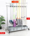 Floor Mounted Broom And Mop Holder Rack With Thick Rubber Clips Movable Cabinet Organizer For Garage Workshop And Kitchen Keeps Mop Drain Rack Handy And Easy Access Tool Corner Storage. Metal rack with wheels holding various cleaning tools.