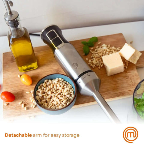 Professional Handheld Immersion Blender Featuring Powerful 400W Motor And Durable Stainless Steel Shaft Perfect For Creamy Soups Rich Sauces And Quick Daily Meal Prep Blends Effortlessly Like A Real Deal Kitchn Champion on a wooden board with pine nuts, olive oil and cheese.