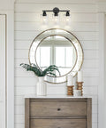 Decorative wall with round mirror, wall light, and greenery on dresser