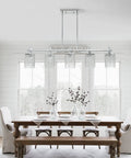 Dining room with chrome crystal linear chandelier over rustic wooden table, featuring Water Ripple Glass Kitchen Island Pendant Light 5 Light Fixture With Matte Black Metal Finish For Modern Kitchens And Open Living Spaces Elevate Your Home Decor And Create A Calm Vibe.