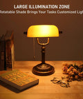 Amber Glass Bankers Desk Lamp With Retro Weighted Base And Old School Vibe on wooden desk with books and flowers