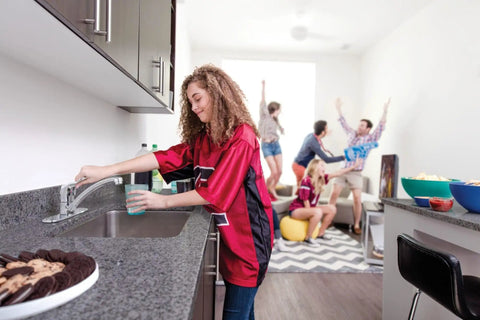 Heavy-Duty Commercial One-Handle Kitchen Faucet in Chrome with 1.5 GPM Flow in use during a social gathering in a modern kitchen