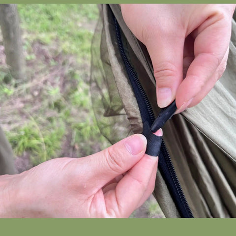 Hands zipping a section of the Camping Hammock Tent With Net And Portable Sleeping Cot For Backpacking And Hiking Travel 3 In 1 All In One Outdoor Gear With Rain Fly Heavy Duty 440 Lbs Capacity
