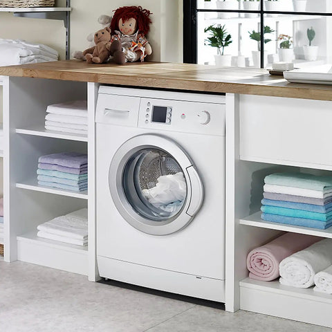 Laundry room with white front-loading washing machine and shelves filled with neatly folded towels.