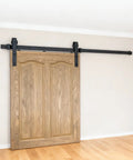 6.6 Ft Black Sliding Barn Door Hardware Kit with wooden door on track, showcasing smooth gliding motion upgrade for home.
