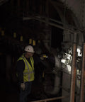 Worker using PolyStinger LED Flashlight With DC Charger And Piggyback Holder, Yellow, 485 Lumens in a dark industrial setting.