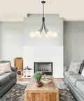 Modern living room with minimalist pendant light above wooden coffee table, featuring a cozy seating area and large windows.