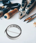 No Fuss Self Adhesive One Meter Steel Metric Track Ruler Tape on a white surface with tools, showing its laid flat design.