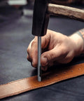 Using Leather Oval Hole Punch 6x5mm Belt Hole Puncher on leather strap with a hammer, precision cutting.