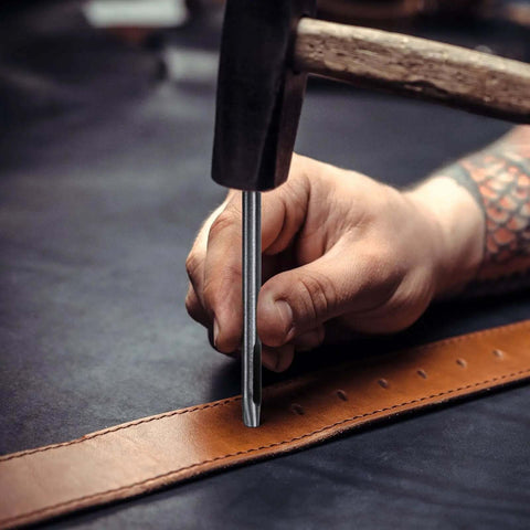Using Leather Oval Hole Punch 6x5mm Belt Hole Puncher on leather strap with a hammer, precision cutting.