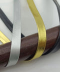 Close-up of 13Ft PU Leather Ito Sageo Rope for Katana Tsuka Wrap, showing black, silver, and gold cords on a wooden stick.