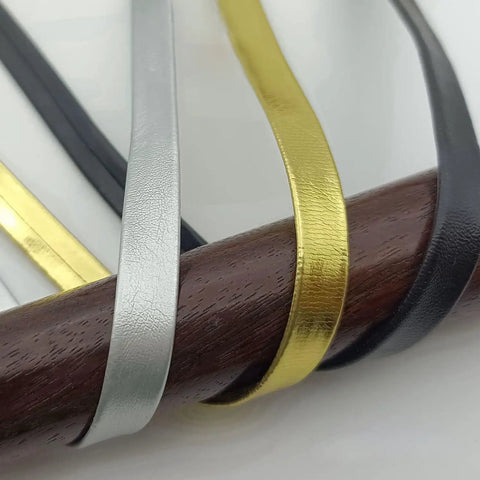 Close-up of 13Ft PU Leather Ito Sageo Rope for Katana Tsuka Wrap, showing black, silver, and gold cords on a wooden stick.