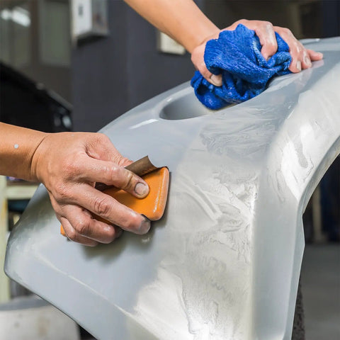 Hand using Pro-Grade 1000 Grit Wet Or Dry Sandpaper Sheets 5-1/2 X 9 In Box Of 25 for sanding car surface in auto body shop.
