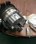 12 Inch Precision Rotary Table Featuring Killer Accuracy 10 Inch 3 Jaw Chuck with reversible jaws and index plates on a wooden table.