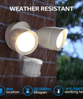 Motion Sensor LED Flood Light With Dual Adjustable Heads For Outdoor Security mounted on brick in rain, lit and weather resistant.
