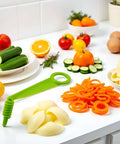 Green handheld spiral slicer; plastic kitchen tool with circular handle, shown with carrot curls and cucumber rounds on white counter.