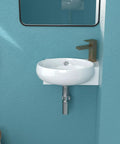 Round white ceramic wall-mounted sink with brass faucet against blue wall