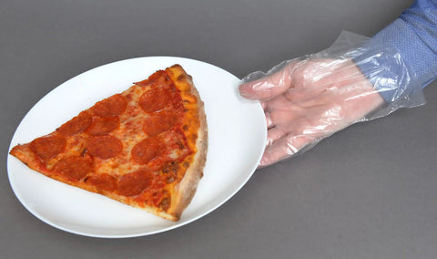 Close-up of hand wearing clear embossed poly glove holding plate with pizza slice, demonstrating textured grip for food handling.
